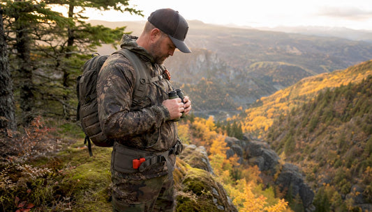 Hunter in tactical gear overlooking forest