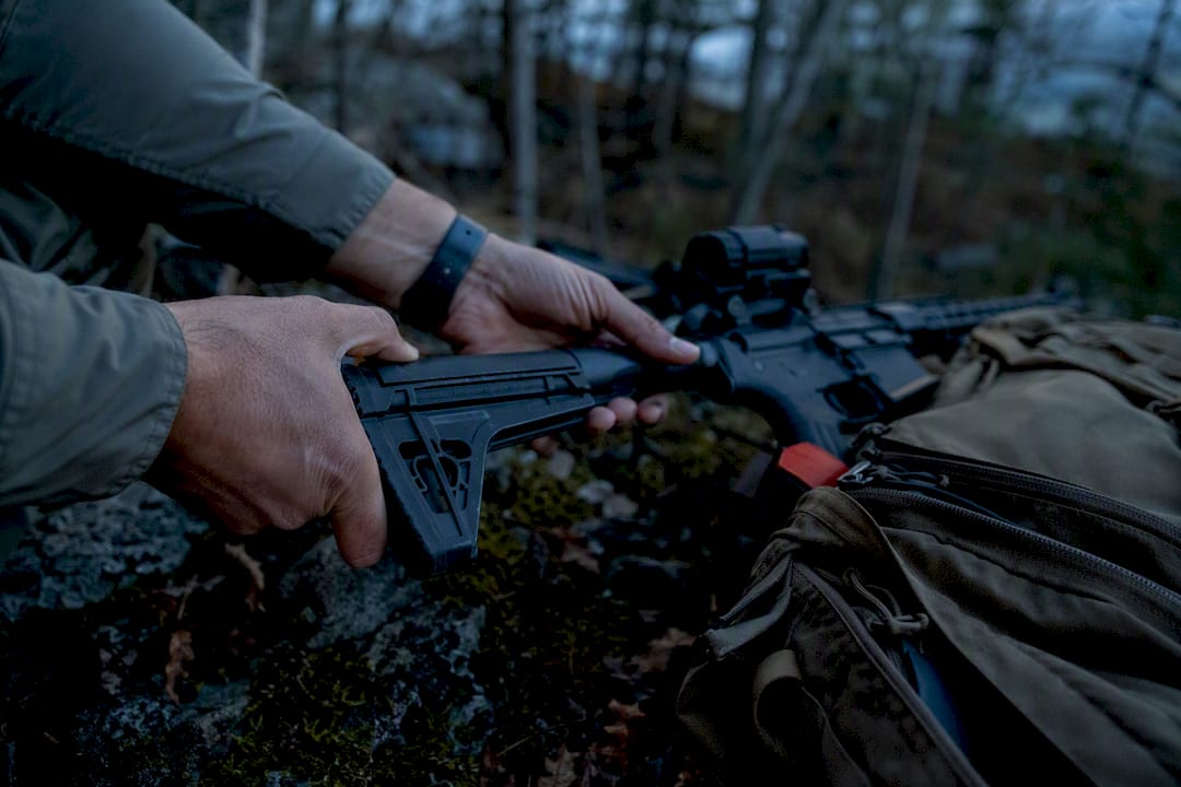 Hands adjusting carbine rifle stock outdoors