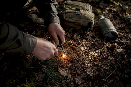 Hand striking ferro rod igniting tinder outdoors